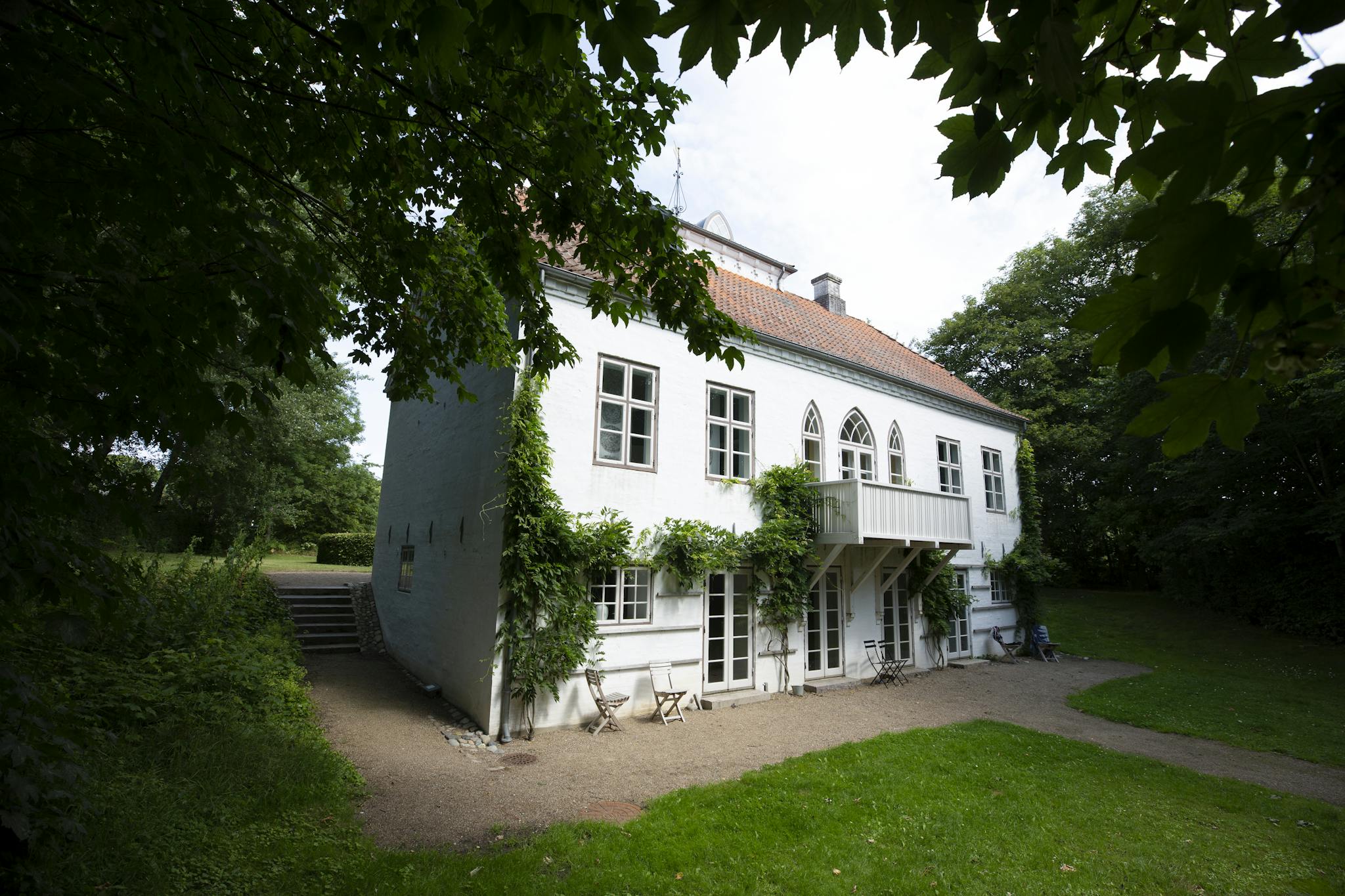 Charming European house with ivy-covered facade set in a lush green landscape, perfect for a serene getaway.